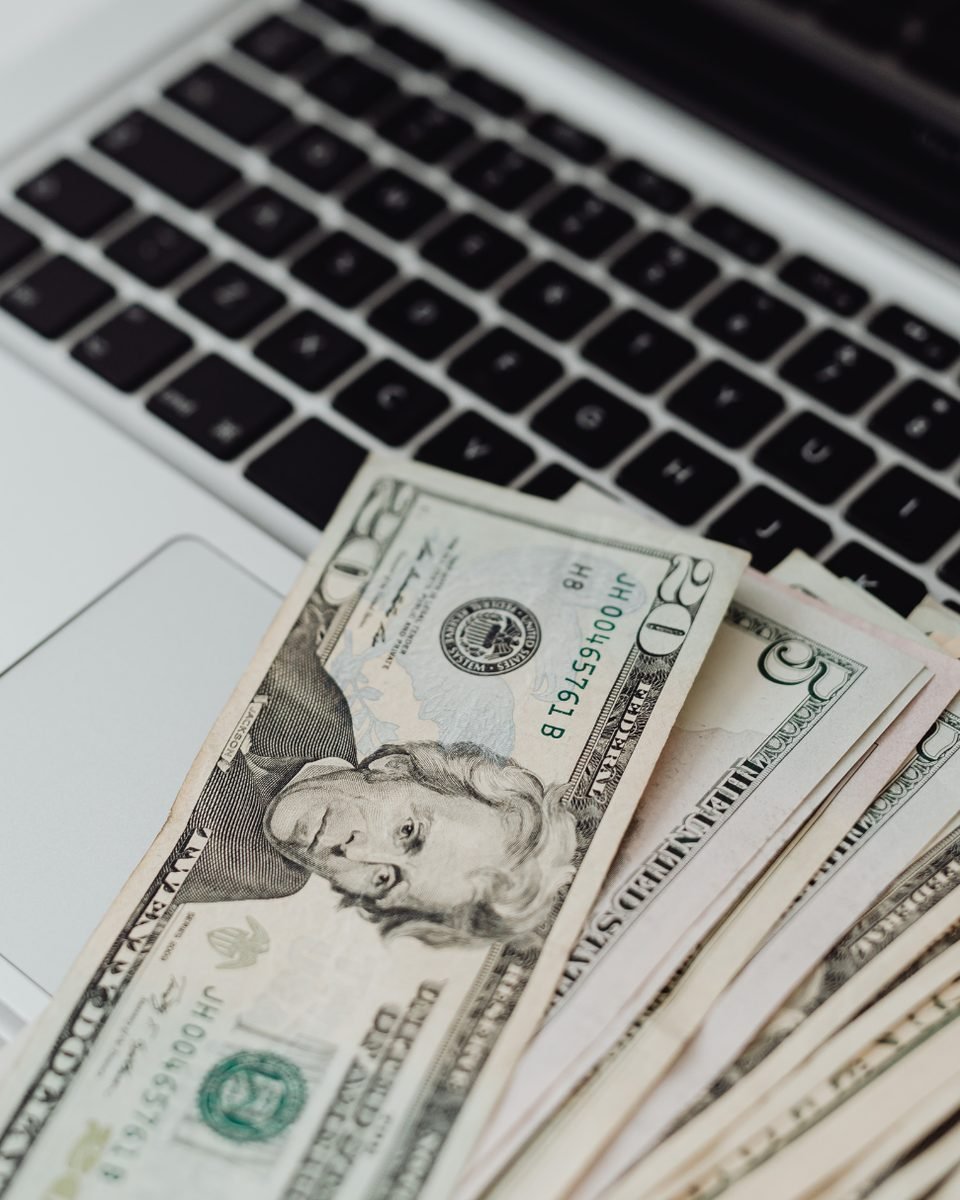 Billetes extendidos sobre el teclado de un portátil.